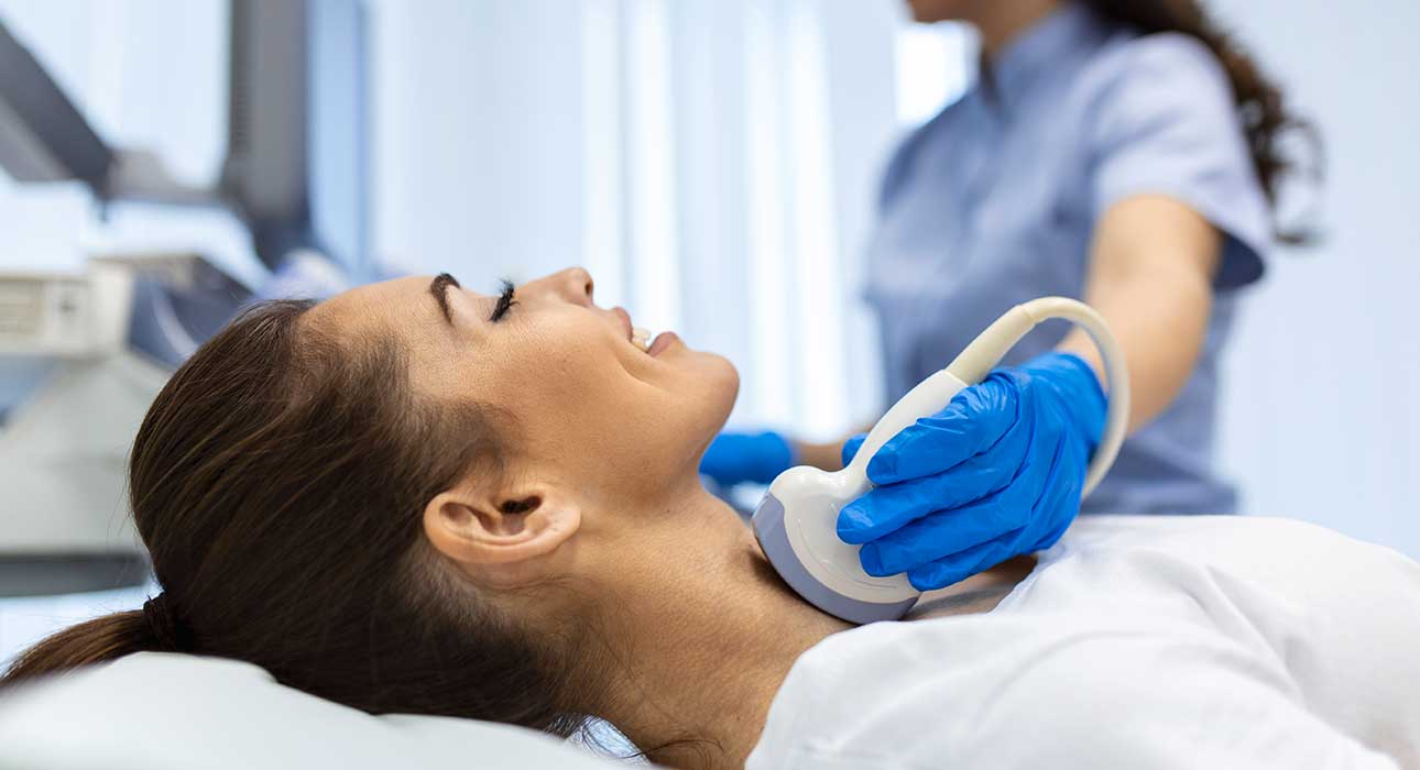 Egy orvos a beteg pajzsmirigyét vizsgálja ultrahanggal.
